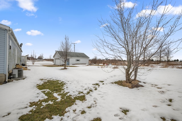 yard layered in snow with a detached garage, central AC unit, and an outbuilding