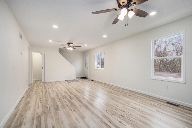 unfurnished living room featuring visible vents, baseboards, and light wood-style flooring