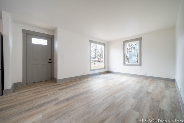 entrance foyer featuring baseboards, light wood finished floors, and a healthy amount of sunlight