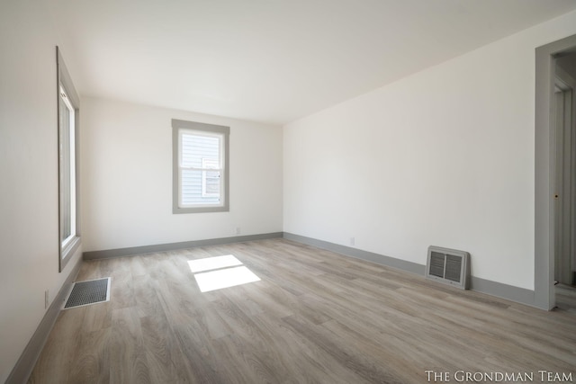 empty room featuring wood finished floors, visible vents, and baseboards