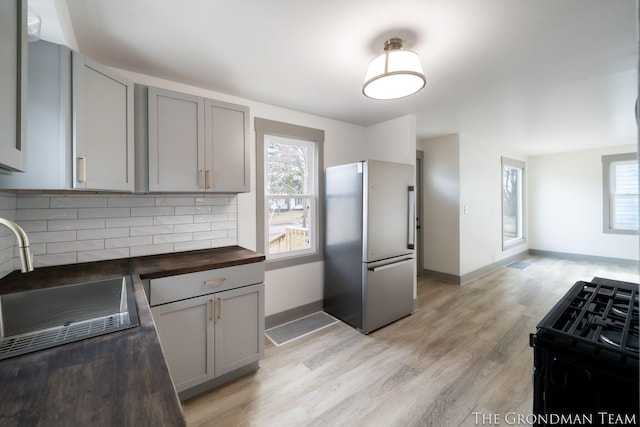 kitchen with black gas range, butcher block counters, high end fridge, and gray cabinetry