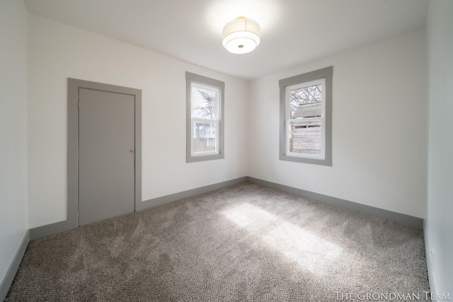 carpeted spare room featuring plenty of natural light and baseboards