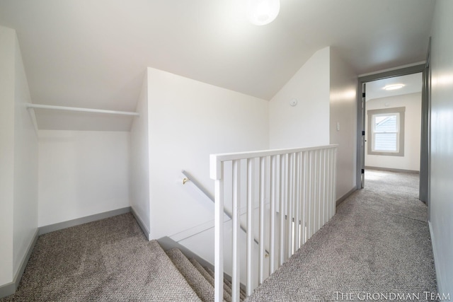 hall featuring lofted ceiling, carpet floors, an upstairs landing, and baseboards