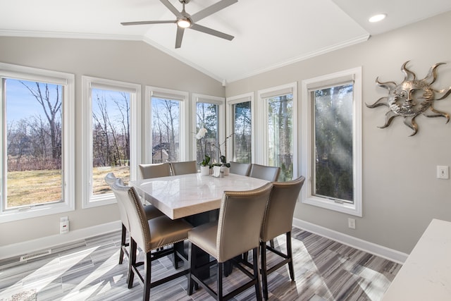 dining area featuring baseboards, a healthy amount of sunlight, crown molding, and vaulted ceiling