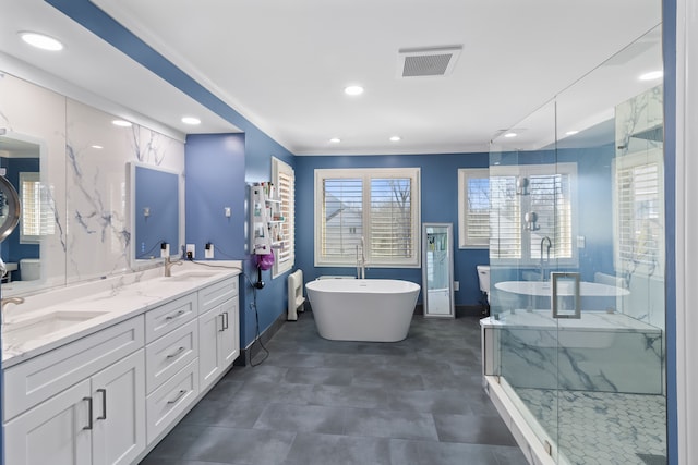 bathroom featuring double vanity, visible vents, a stall shower, and a freestanding tub