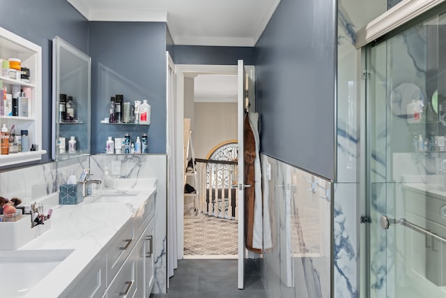 bathroom with a sink, double vanity, a shower with shower door, and ornamental molding