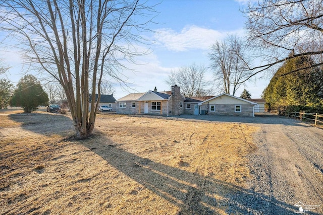 ranch-style home featuring driveway, a chimney, and fence