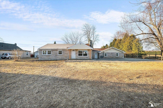 single story home featuring stone siding, a chimney, and fence