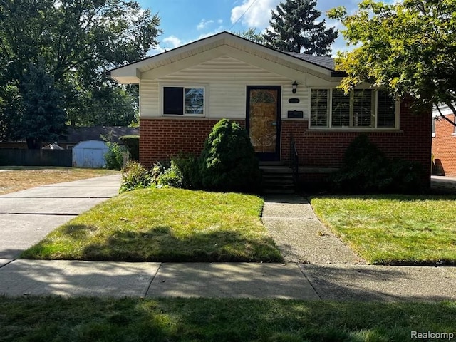 bungalow with an outdoor structure, a storage unit, a front lawn, and brick siding