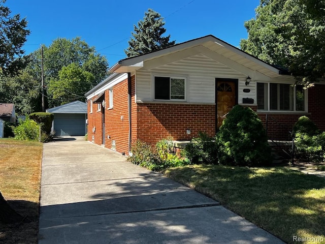 view of front facade featuring brick siding, a front yard, a detached garage, and an outbuilding