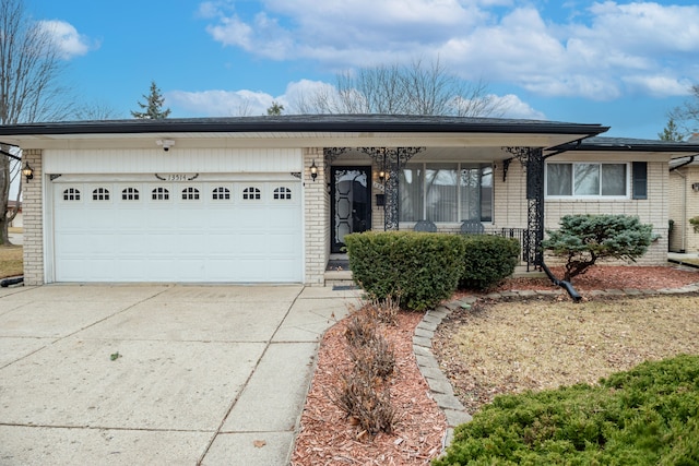 single story home with driveway, brick siding, and an attached garage