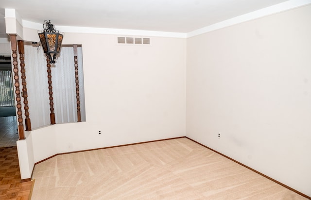 empty room with ornamental molding, visible vents, and baseboards