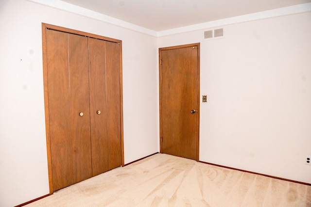 unfurnished bedroom featuring light carpet, visible vents, and a closet