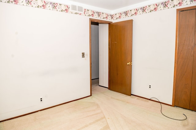 spare room featuring light carpet, visible vents, and baseboards