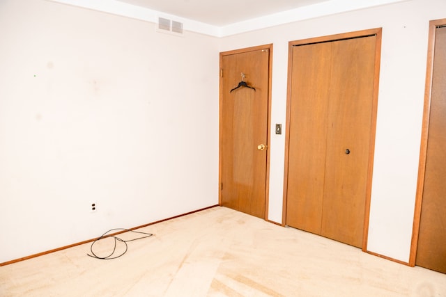 unfurnished bedroom featuring baseboards, two closets, visible vents, and light colored carpet