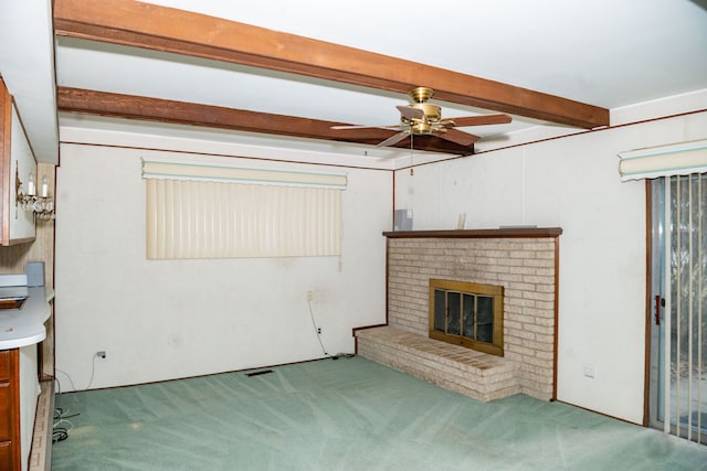 unfurnished living room with beamed ceiling, a brick fireplace, carpet flooring, and a ceiling fan