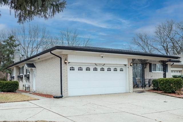 exterior space featuring a garage, concrete driveway, brick siding, and a chimney