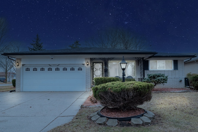 ranch-style home featuring a garage, concrete driveway, and brick siding