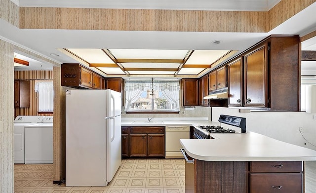 kitchen with light countertops, a sink, separate washer and dryer, white appliances, and under cabinet range hood