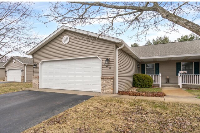 ranch-style house with covered porch, driveway, brick siding, and an attached garage