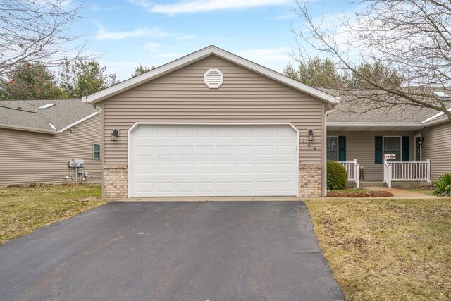 ranch-style home with brick siding, covered porch, an attached garage, a front yard, and driveway