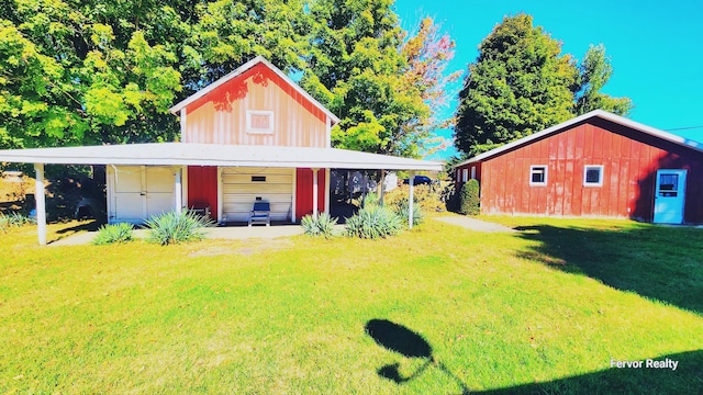 rear view of house featuring driveway, a lawn, an outdoor structure, and a detached garage