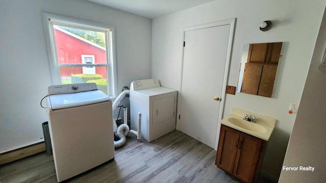 laundry room with laundry area, washer and dryer, light wood-style floors, and a sink