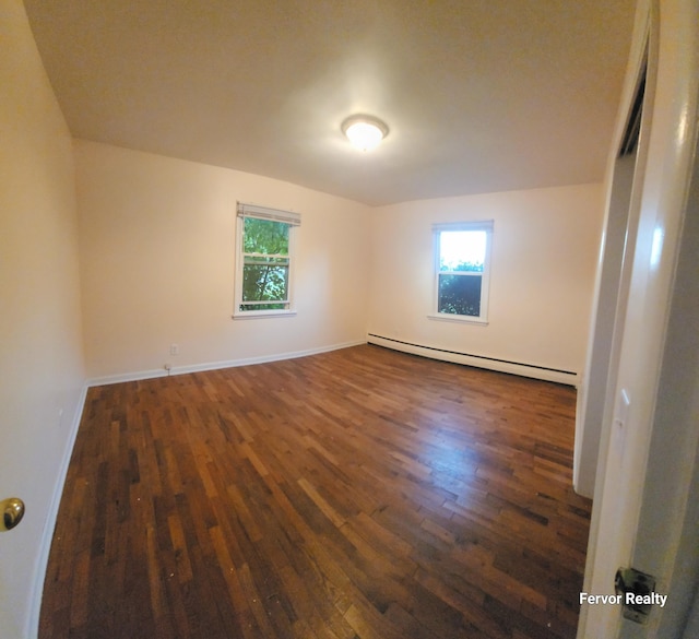 spare room featuring dark wood-style floors, a baseboard radiator, a wealth of natural light, and baseboards