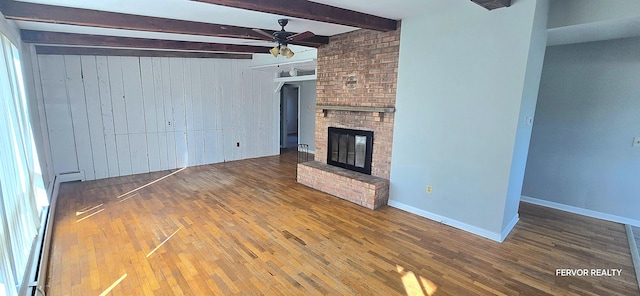 unfurnished living room featuring baseboards, a ceiling fan, wood finished floors, a fireplace, and beam ceiling