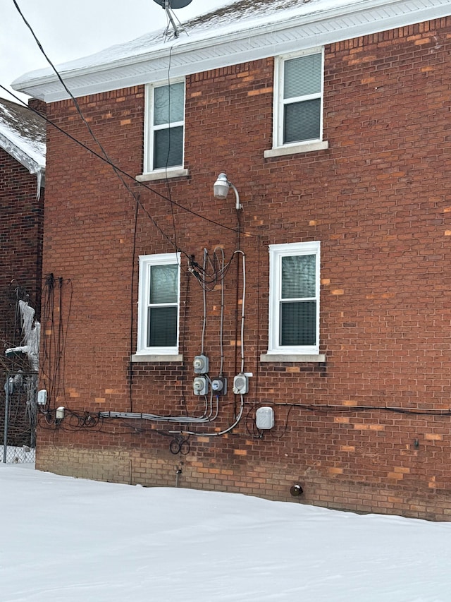 view of snow covered exterior with brick siding