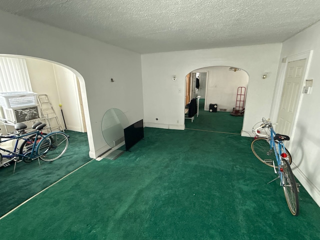 interior space featuring arched walkways, a textured ceiling, and carpet floors