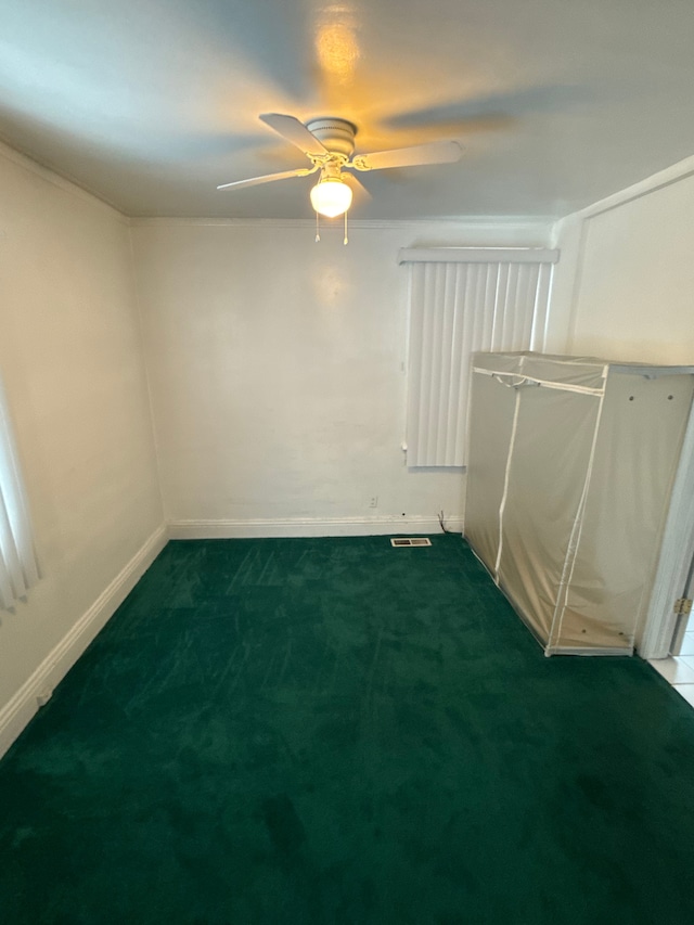 carpeted empty room with a ceiling fan, visible vents, and baseboards