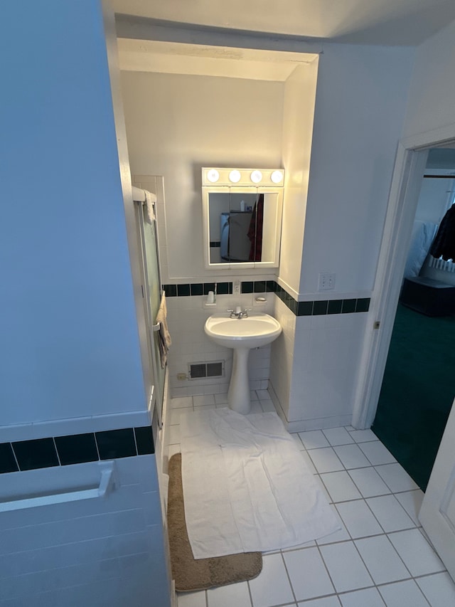 bathroom featuring tile patterned flooring, tile walls, visible vents, and wainscoting