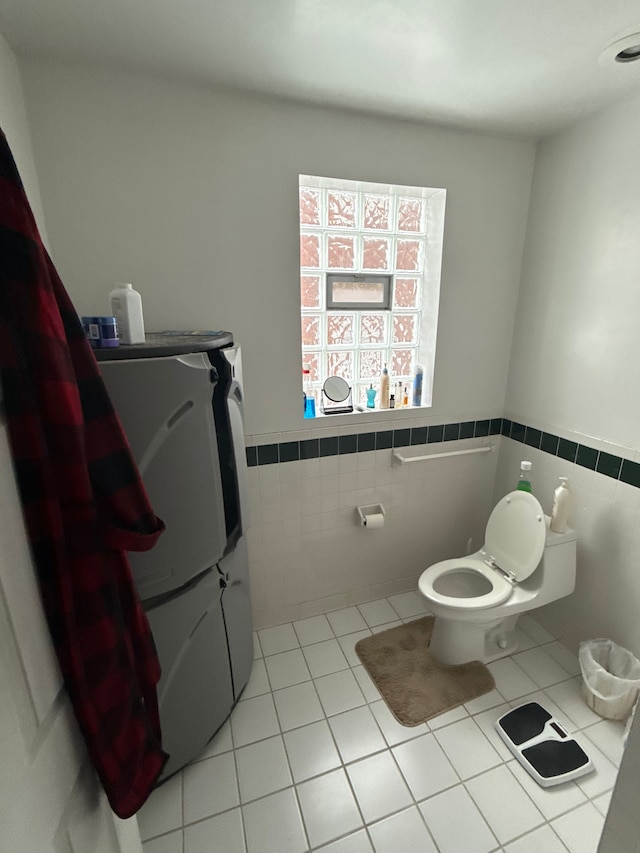 bathroom featuring tile patterned floors, toilet, tile walls, and wainscoting