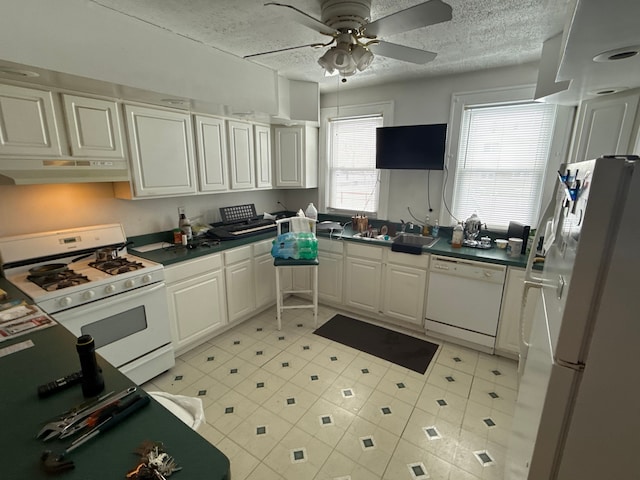 kitchen featuring under cabinet range hood, a sink, a textured ceiling, white appliances, and white cabinets