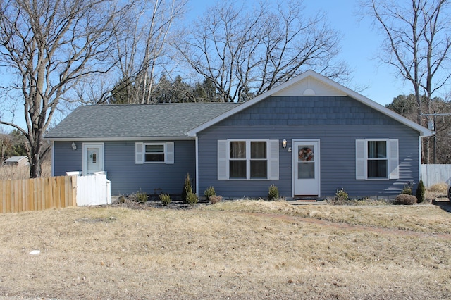 ranch-style house featuring roof with shingles and fence