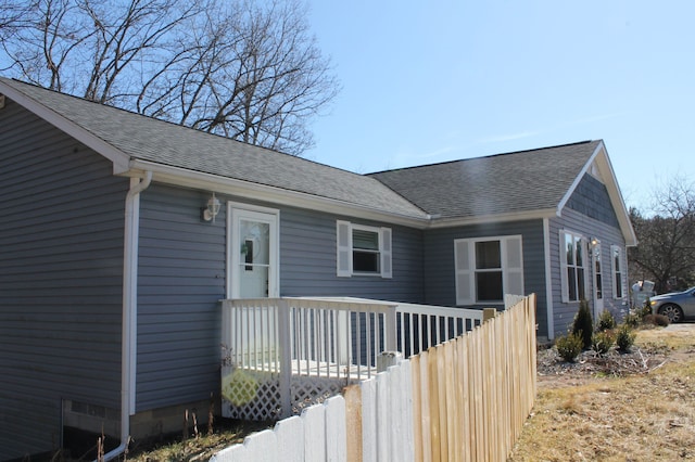 view of front of property with crawl space, a shingled roof, and fence