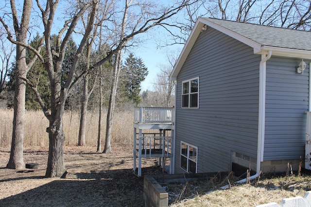 view of side of property featuring roof with shingles and a deck