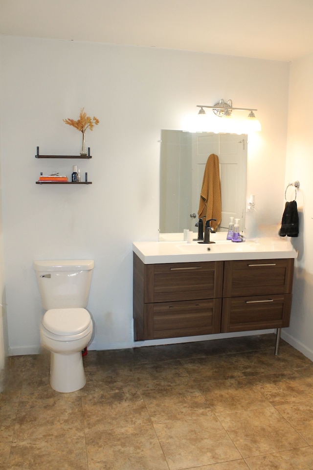 bathroom with baseboards, toilet, and vanity