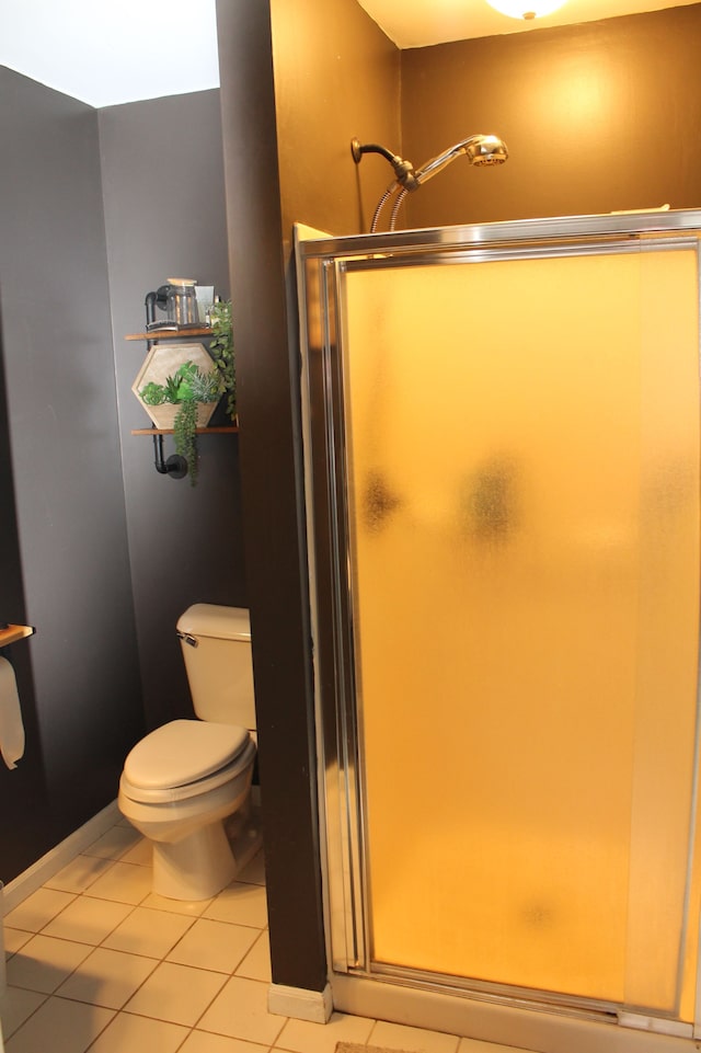 bathroom featuring tile patterned floors, toilet, and a shower stall