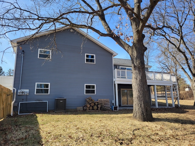 back of property with a deck, a yard, fence, and central AC