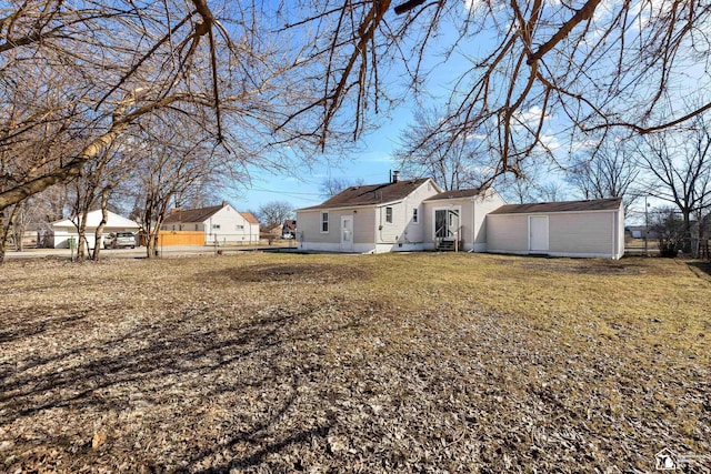 back of house featuring entry steps, a yard, and fence