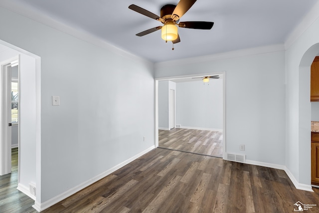 empty room featuring a ceiling fan, baseboards, visible vents, arched walkways, and dark wood-type flooring