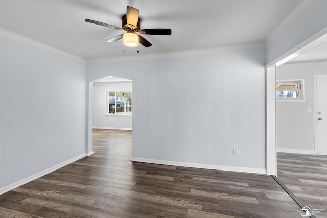 spare room with a ceiling fan, wood finished floors, baseboards, and arched walkways