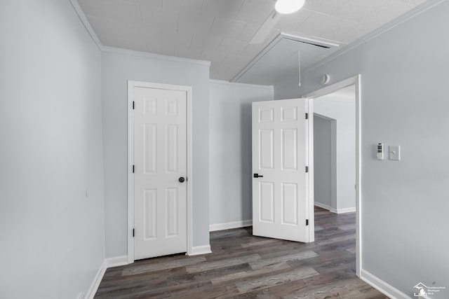 interior space with wood finished floors, attic access, baseboards, and ornamental molding