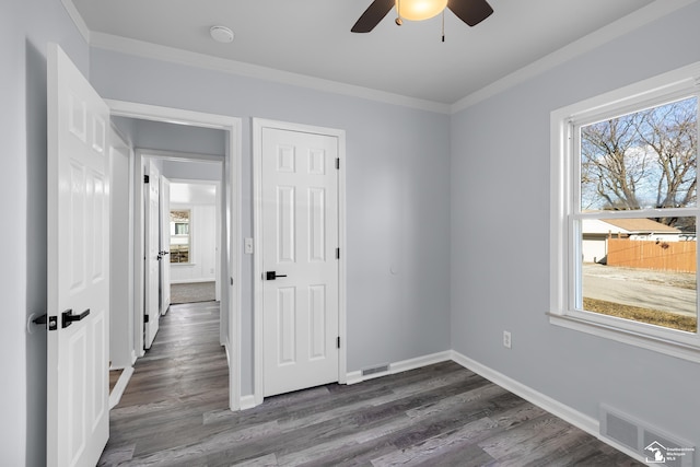 unfurnished bedroom with visible vents, dark wood-type flooring, baseboards, and ornamental molding