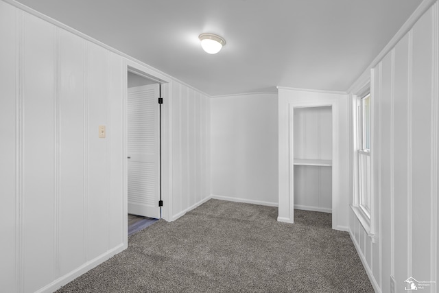 spare room with baseboards and dark colored carpet