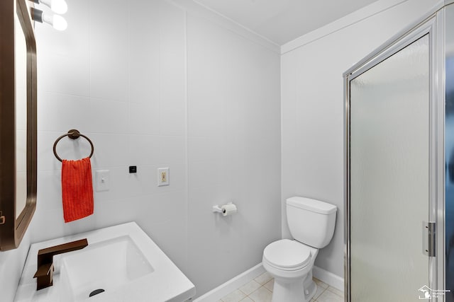 bathroom with ornamental molding, a sink, a shower stall, tile patterned floors, and toilet