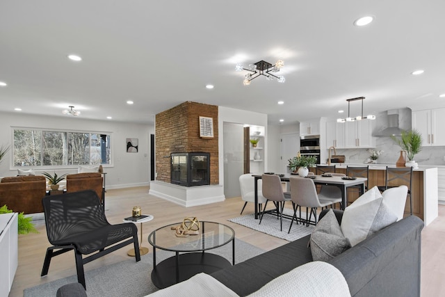 living room with light wood-style flooring, recessed lighting, a multi sided fireplace, and baseboards