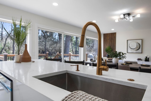 kitchen featuring light stone counters, recessed lighting, and a sink